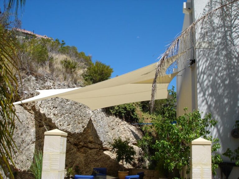Cream shade sail over a patio beside a limestone wall