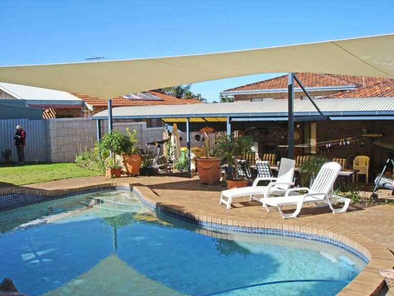 Cream shade sails over a pool and paved entertaining area