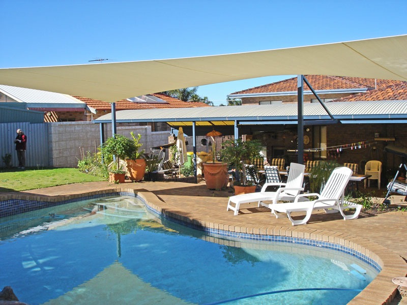 Cream shade sails over a pool and paved entertaining area