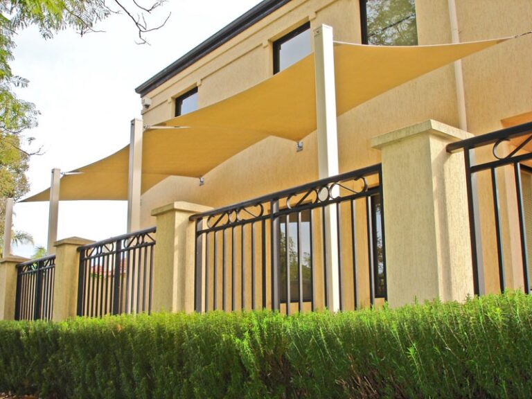 Cream shade sails over a two-storey home’s front balcony
