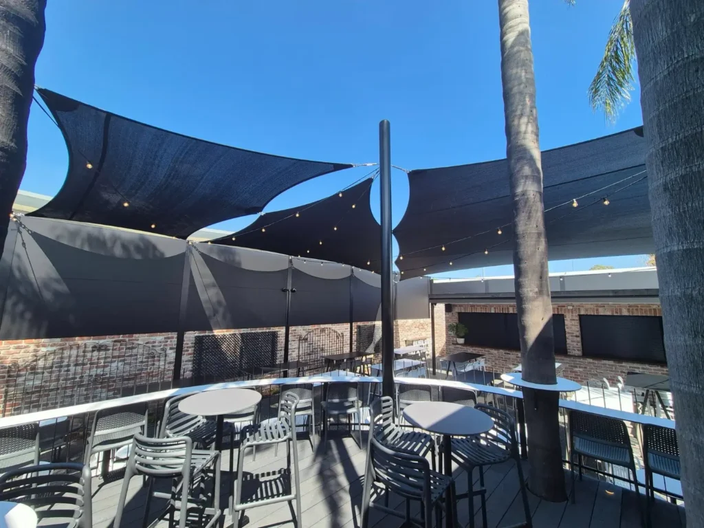 Black shade sails over an outdoor dining area