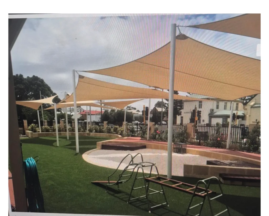 Cream shade sails over a playground with outdoor fitness equipment