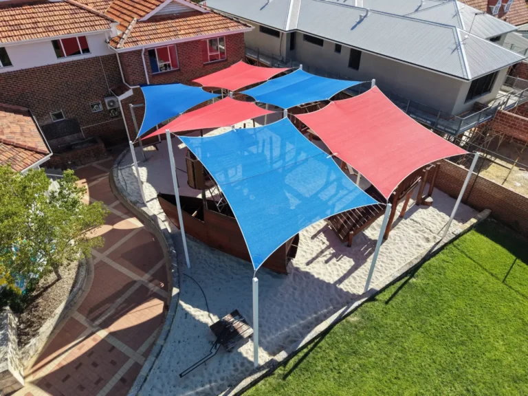 Red and blue shade sails over an outdoor play area